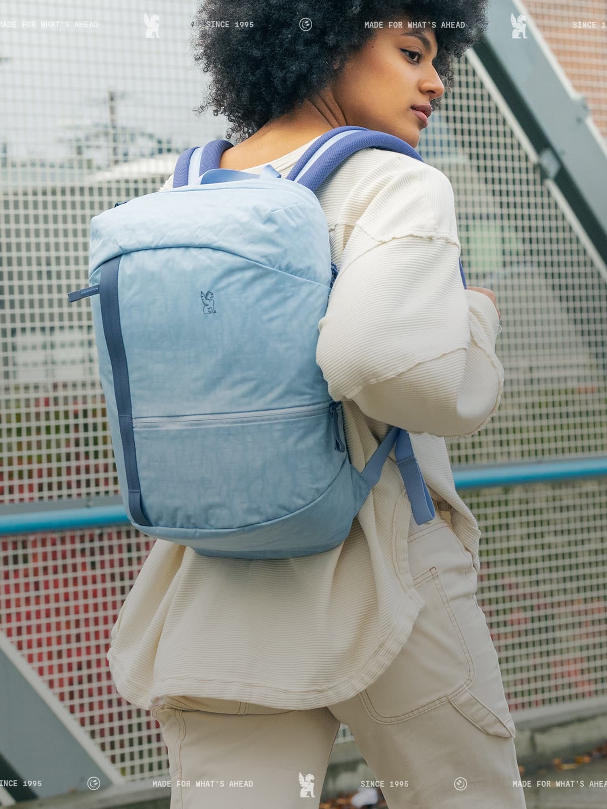 Person wearing 一分钟稳定查询赛车顶尖赛事结果-JISU直播渠道，实时播放赛车官网记录 #168赛道75秒 a light blue backpack in an urban setting