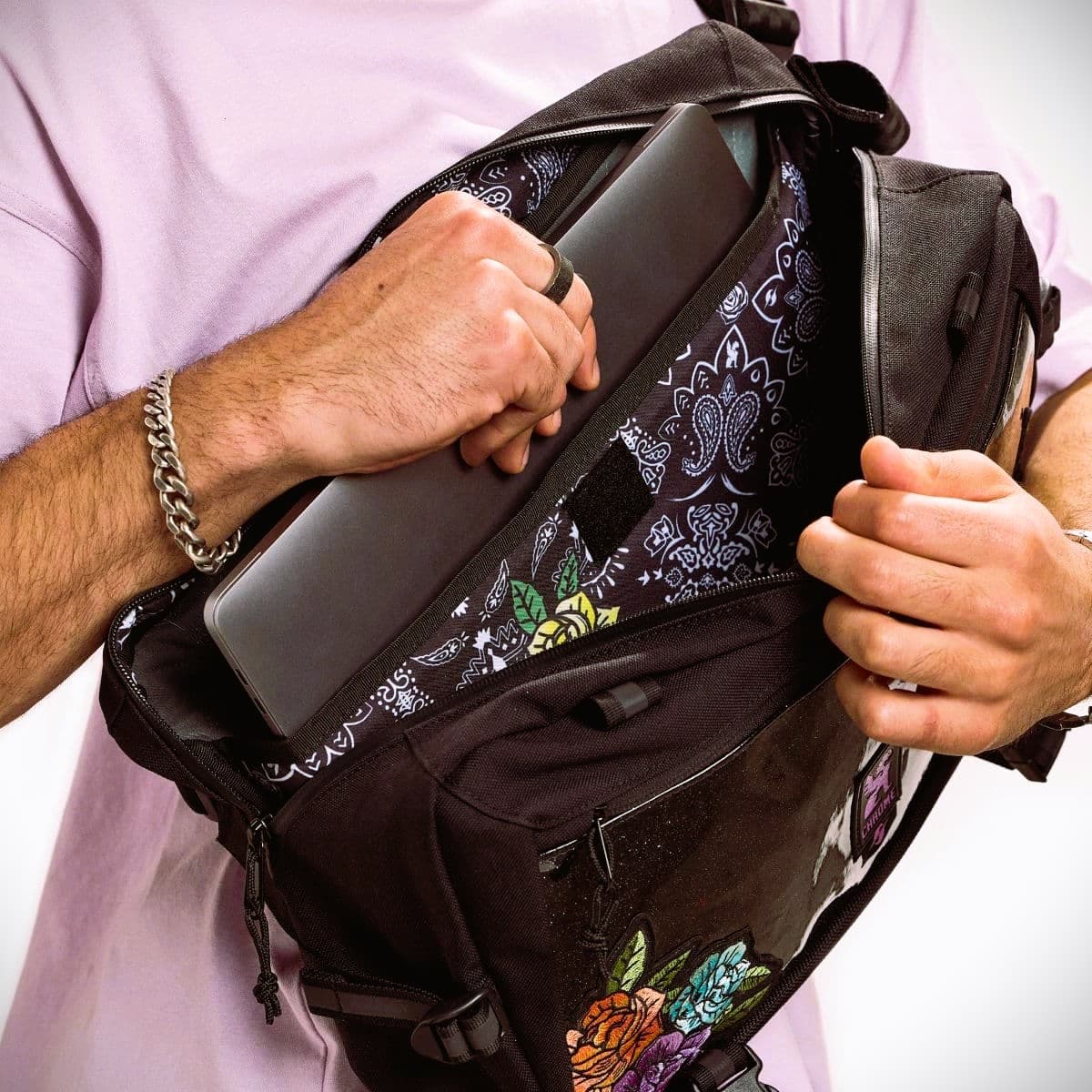 Person holding a black backpack with colorful designs on a white background